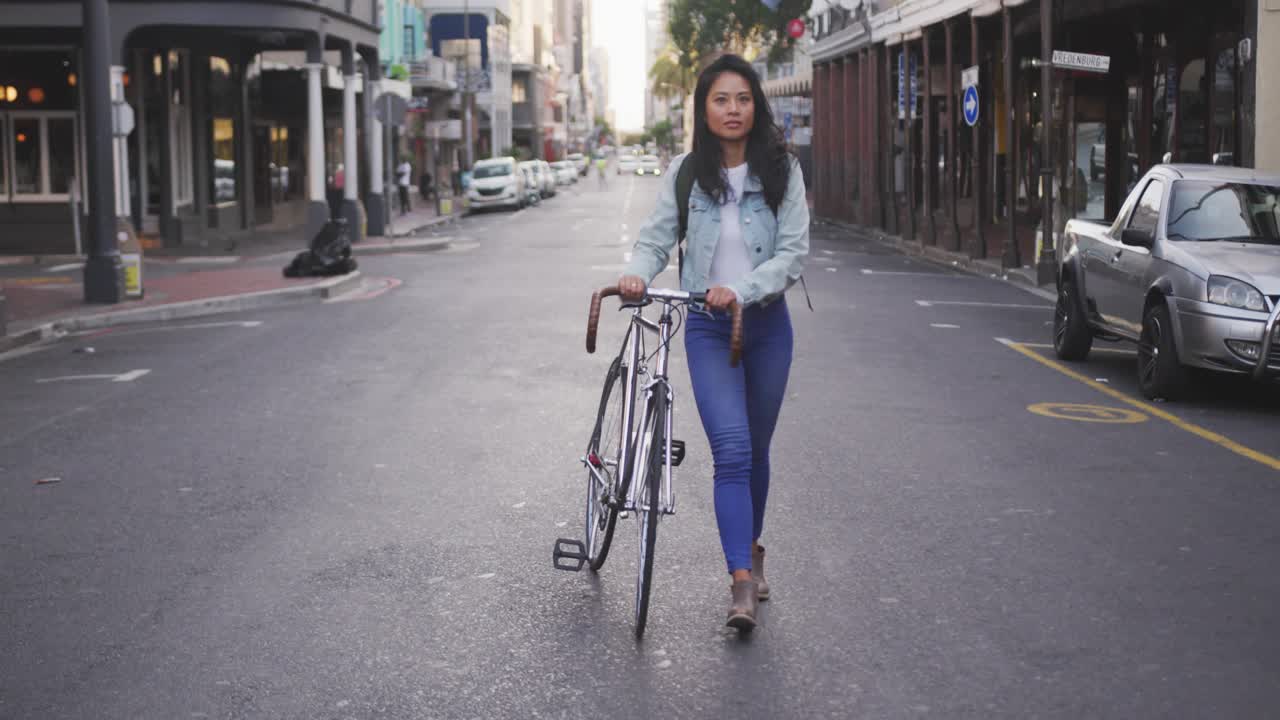 Mid-adult woman commuting, pushing bicycle center street while generating finance charts over torso