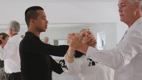 mixed race male dance teacher taking a ballroom dancing class at a dance studio