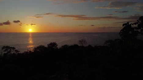 Un-Dron-Aéreo-Descubre-La-Fascinante-Puesta-De-Sol-En-La-Playa-De-Uvita-En-Costa-Rica:-Un-Encantador-Sol-Anaranjado-Que-Proyecta-Su-Brillo-Sobre-El-Mar,-Mostrando-Una-Vibrante-Belleza-Natural