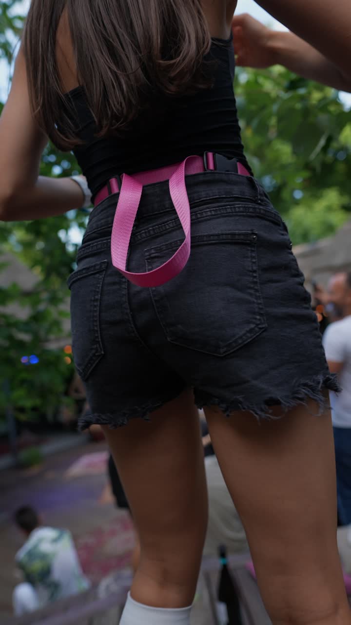 Mulher de shorts jeans e cinto rosa em uma festa