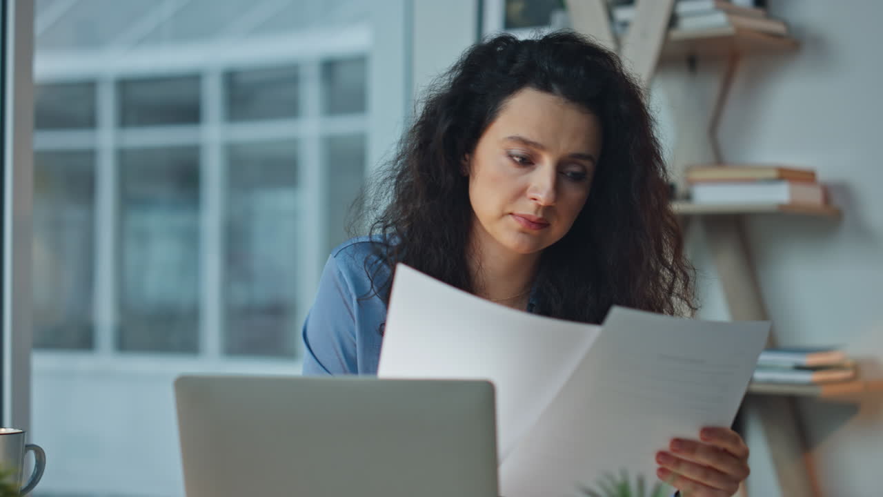Serious executive analyzing report in evening office. Frustrated woman closing