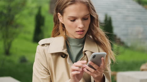 feliz estudiante caucásica usando el teléfono inteligente al aire libre.