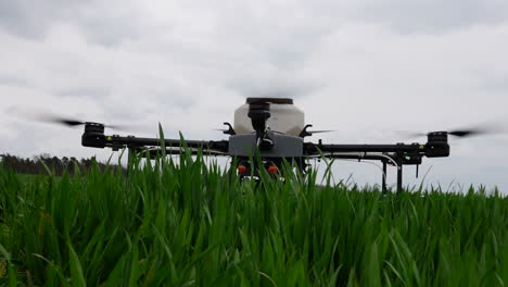 agriculture drone with tank landing in green farming field, close up