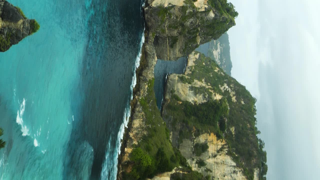 Vertical panorama shot of the beautiful cliffs in front of diamond beach on nusa penida overlooking the blue sea on a beautiful morning