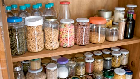 Wooden-cupboard-filled-with-jars-of-spices-and-cereals,-slide-reveal