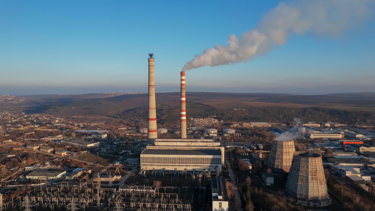 Aerial drone timelapse view of thermal power plant in Chisinau at sunset, Moldova. View of pipes with felling steam, cityscape