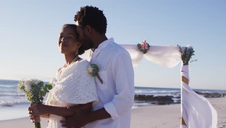 african american couple in love getting married, embracing and smiling on the beach