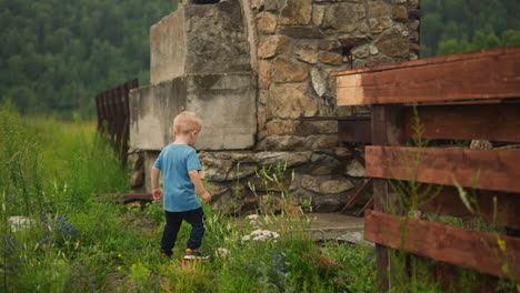 clumsy little boy lifts up on ground for braizer in yard