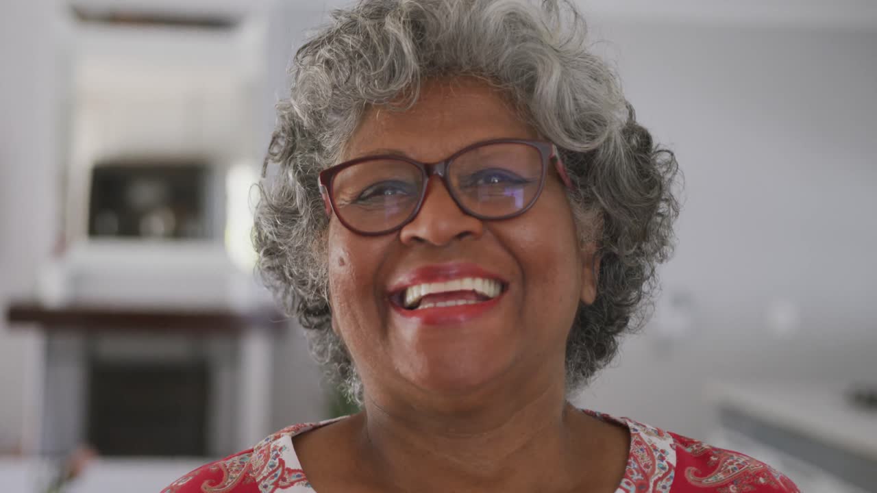 시니어 아프리카계 미국인 여성이 사회적 거리를 유지하면서 카메라에 미소 짓고 있습니다.