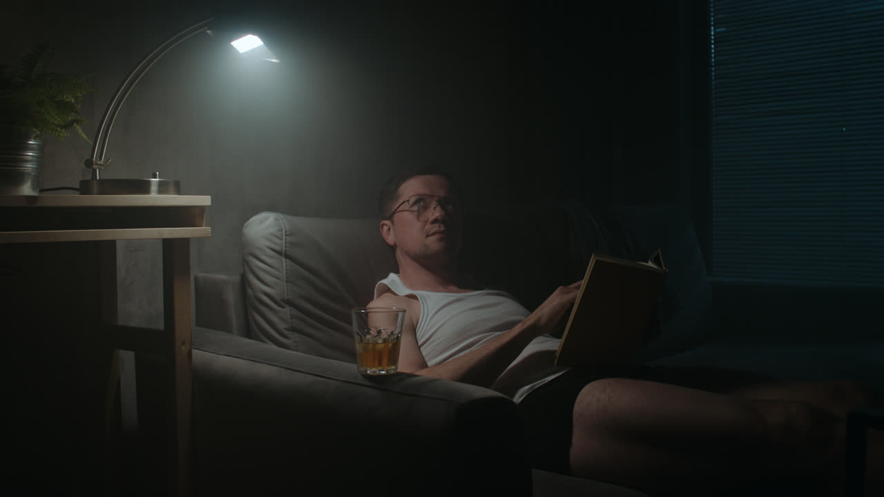 En trist mand læser en bog om natten i sit undertøj