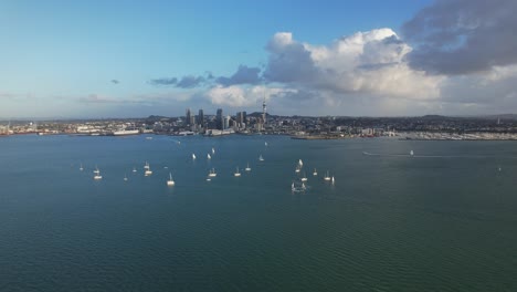 aerial view of sailboats in the calm waters of waitemata harbour with auckland cbd in the distance in new zealand