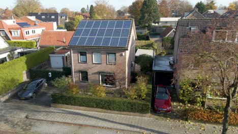 jib down of small detached house with a rooftop filled with solar panels and an electric car charging in parking lot