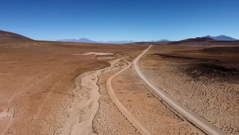 el camino de tierra atraviesa el vasto desierto del altiplano en las remotas montañas bolivianas.