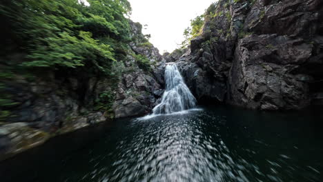 cascading waterfall through rugged cliffs with lush greenery in a serene natural setting