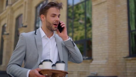 man answering call smartphone outside. businessman walking to work on street