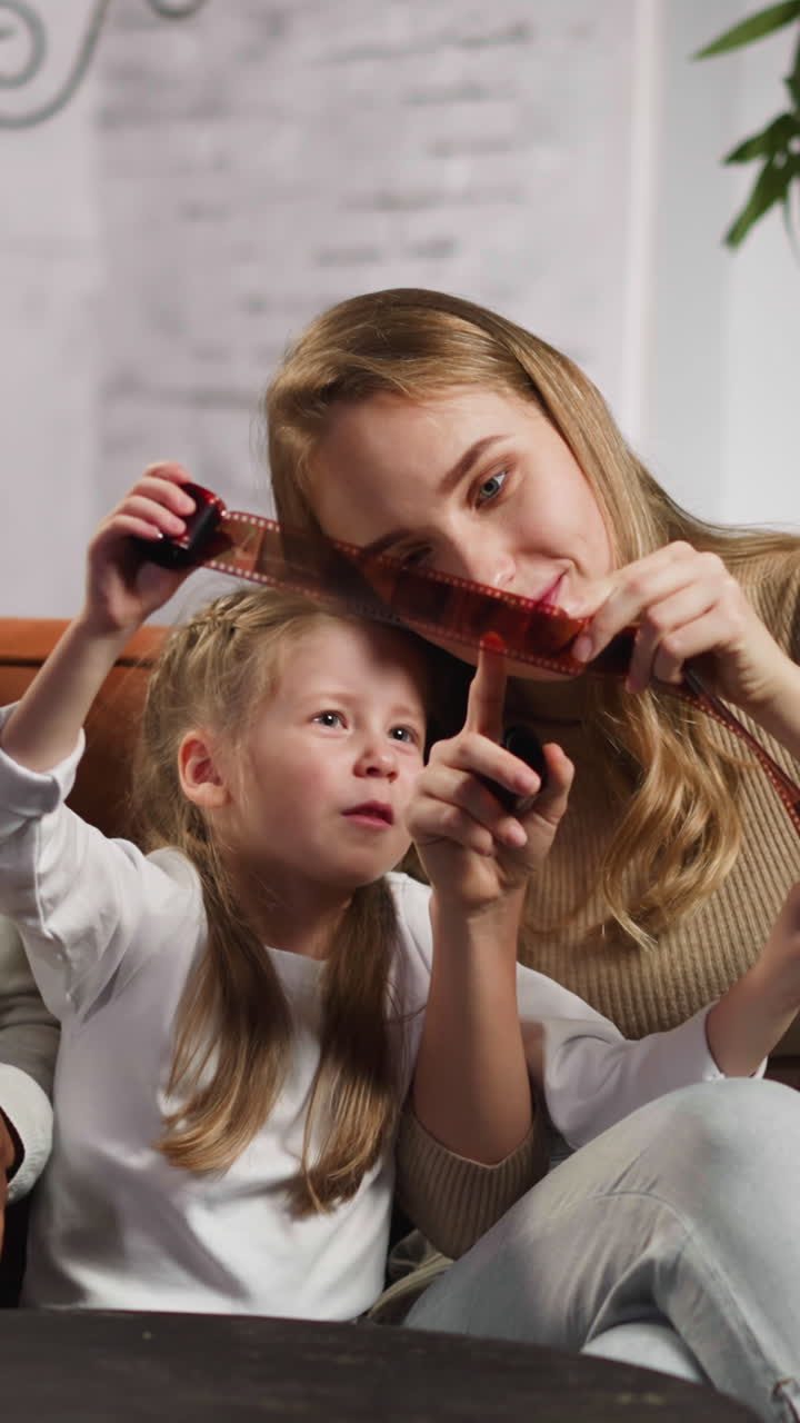 Black guy with white wife and pretty little daughter recall relatives looking at rolled negatives on couch in stylish living room slow motion