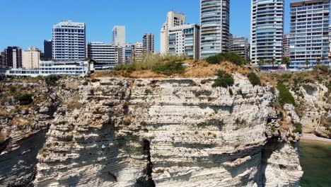 Edificios-Modernos-En-La-Costa-Mediterránea-En-Beirut,-Líbano,-Vista-Desde-El-área-Junto-A-Las-Famosas-Rocas-Raouche---Retroceso-Aéreo