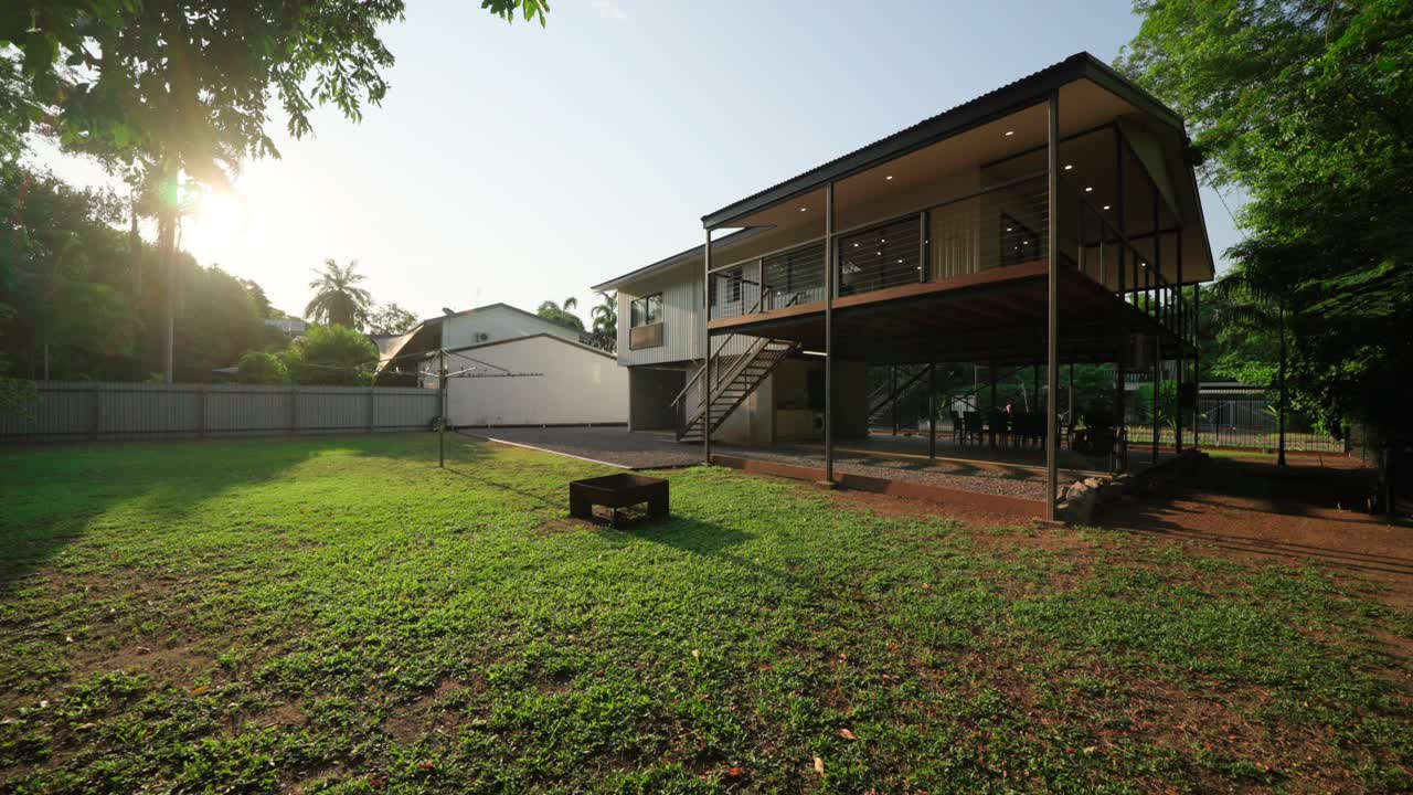 Exterior view of two-story Darwin home with spacious yard, perfect for real estate, pullback at sunset to establish lawn with open air patio decks and large glass windows