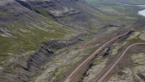 Paso-Elevado-Aéreo-Serpenteante-Con-Vehículos-Conduciendo-En-Las-Montañas-Islandesas-Durante-El-Día---Estableciendo-Vuelo-De-Drones