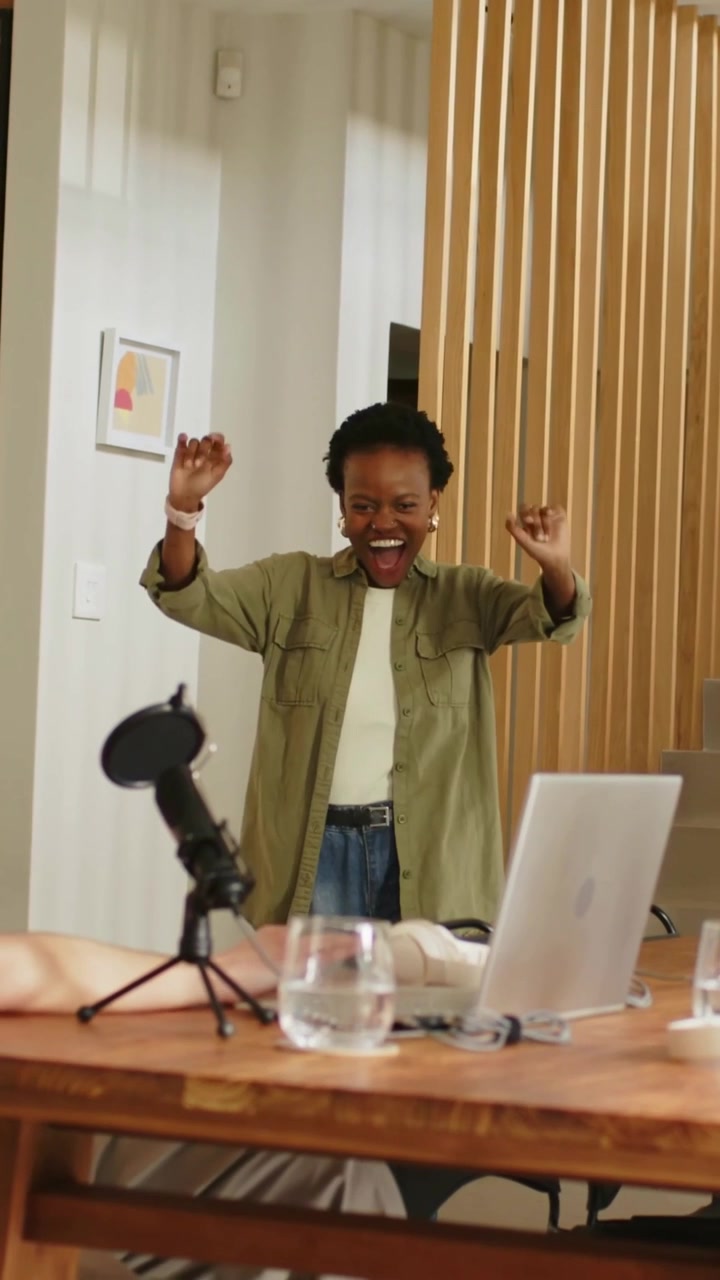 Vertical video: Coming from door woman in olive top raising arms for hug at home desk laptop mic