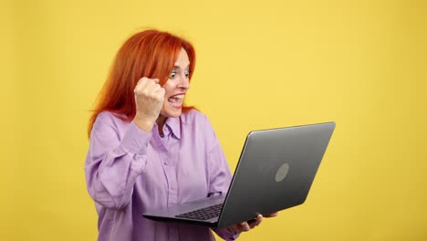 excited red-haired woman celebrating success with laptop