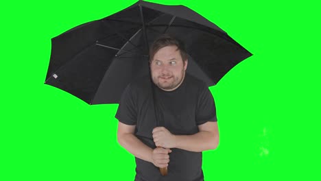 bearded caucasian male under black umbrella shacking in cold temperature wearing half sleeve t-shirt