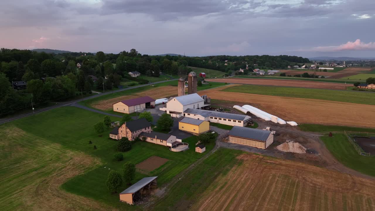 Golden hour in rural district of american town. American farmstead with barn,stable and agricultural farm fields at sunset.Springtime season in United States. Pennsylvania State, Aerial view.