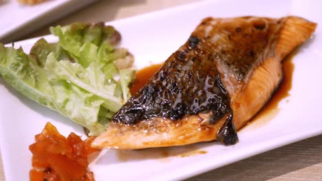 Panorámica-De-Derecha-A-Izquierda-Del-Marco-Que-Muestra-Una-Fuente-De-Filete-De-Salmón-A-La-Parrilla,-Glaseado-Con-Salsa-Teriyaki