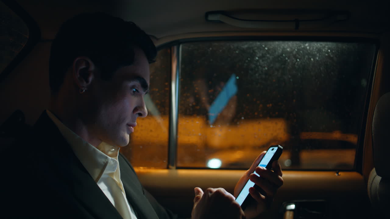 심각한 보스 휴대 전화 스와이핑 저녁 자동 클로즈업. 휴대 전화를 스크롤하는 남자