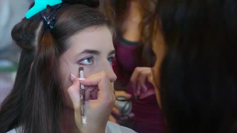artista de maquillaje aplicando eyeliner a una mujer joven