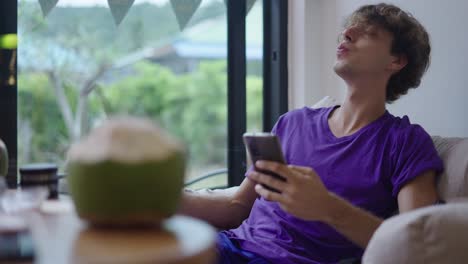 young man smoking and using phone while relaxing indoors
