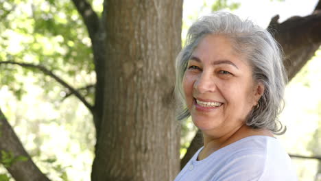 Retrato-De-Una-Feliz-Mujer-Birracial-Mayor-Con-Pelo-Gris-En-La-Naturaleza-Soleada,-Espacio-Para-Copiar,-Cámara-Lenta