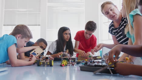 students with teachers in after school computer coding class learning to program robot vehicle