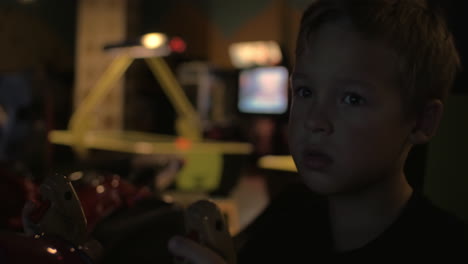 vista de cerca de un niño pequeño jugando a un videojuego de arcade en el centro de juegos