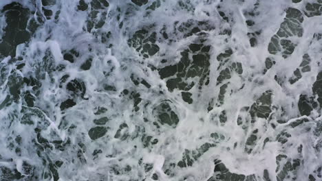 overhead view of rough waves crashing over seashore