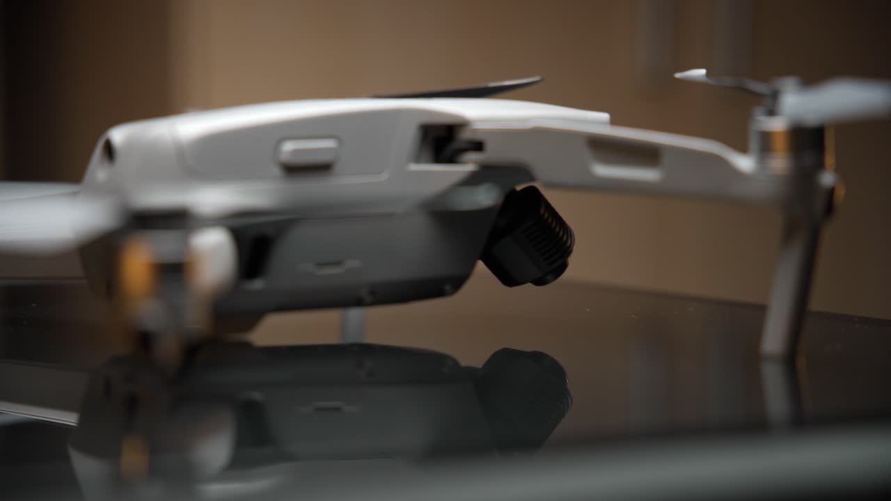 video cinematográfico de un dron encendido iluminado con una luz suave desde arriba y luces naranjas en el fondo, filmado en 4k con movimiento de cámara