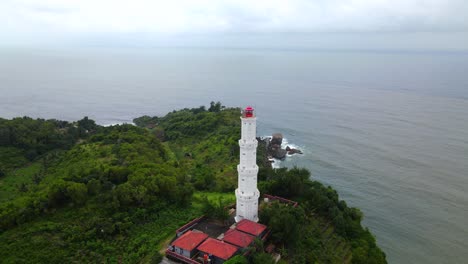 Vista-Aérea-Del-Faro-Blanco-En-La-Colina-Frente-Al-Océano-En-Yogyakarta,-Indonesia