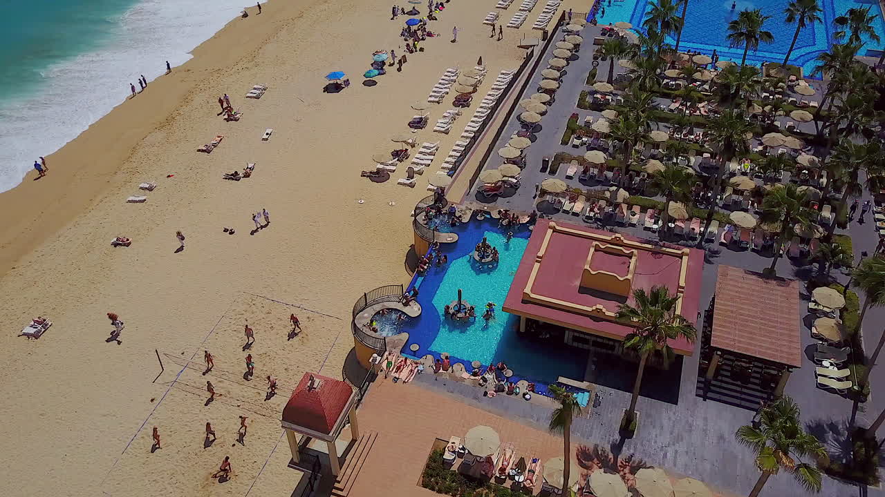 Sorvolo con drone di una piscina e della spiaggia di un resort a Cabo San Lucas, Messico.