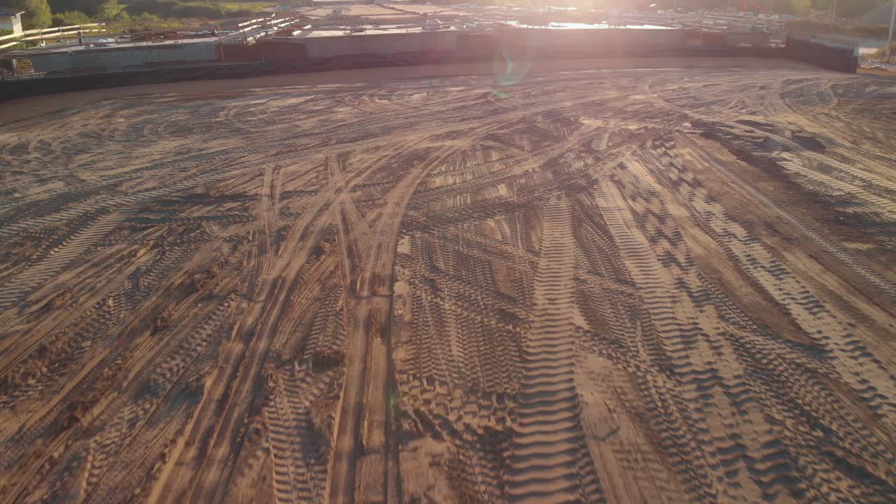 Aerial fly over modern road construction site with sun flare