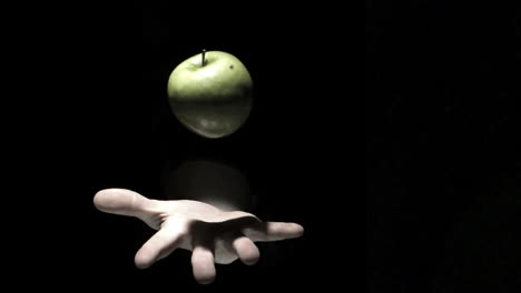 hand tossing a green apple