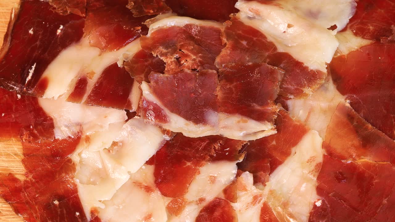 lonchas grasas de jamón serrano en una tabla de madera, vista de cerca