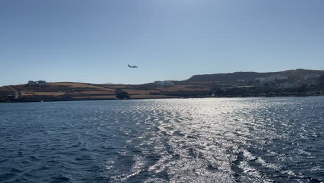 greece, astypalea island, footage is taken from maltezana beach of a flight landing to the airport in the island. airport is not visible just the landing process of the flight over the sea and land.
