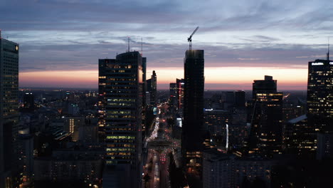Backwards-reveal-of-downtown-skyscrapers.-Silhouette-of-tall-office-buildings-against-colourful-twilight-sky.-Warsaw,-Poland