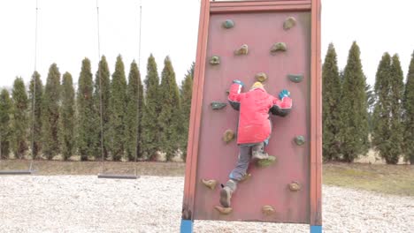 niño pequeño trepando en un marco de escalada en un patio de recreo almacen de video