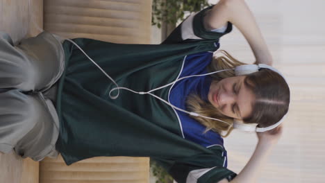 video vertical de una joven feliz escuchando música con auriculares.
