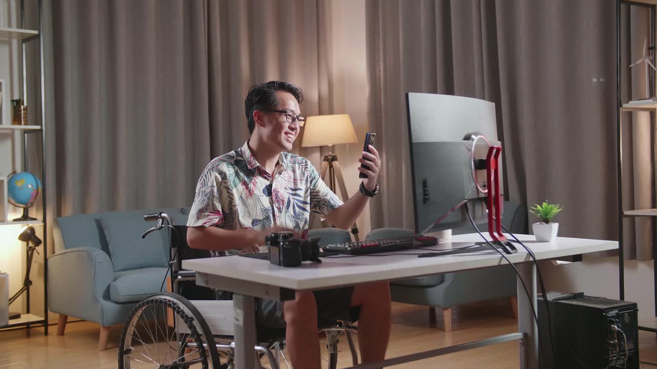 체어에 앉은 남자가 스마트폰과 컴퓨터를 사용하고 있습니다.