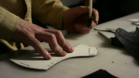 artisan man making holes. close up leather manufacturer working with awl