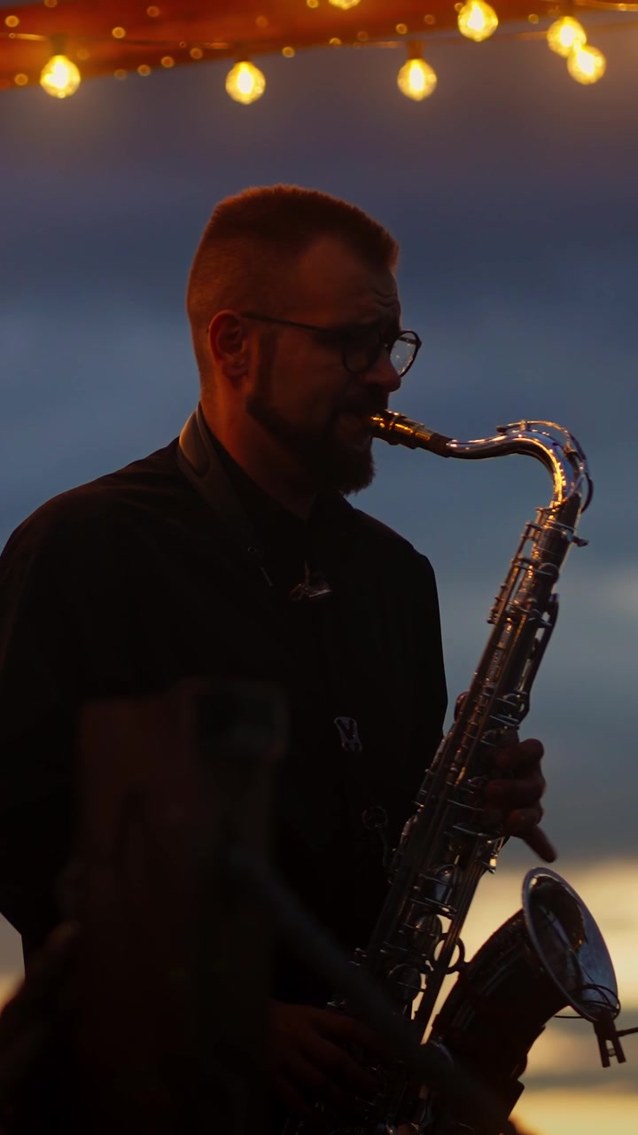 Sassofonista in silhouette a un'esibizione serale all'aperto