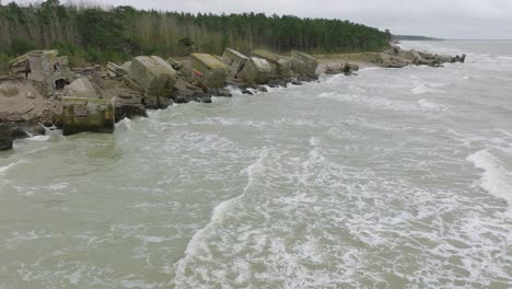 Luftaufnahmen-Von-Verlassenen-Befestigungsgebäuden-Am-Meer-In-Den-Nördlichen-Festungen-Von-Karosta,-Ostseeküste,-Große-Wellen,-Bewölkter-Tag,-Zeitlupe,-Drohnenaufnahme,-Die-Sich-Vorwärts-Bewegt