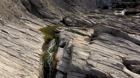 backwards drone flight over some stones and a waterfall at daytime